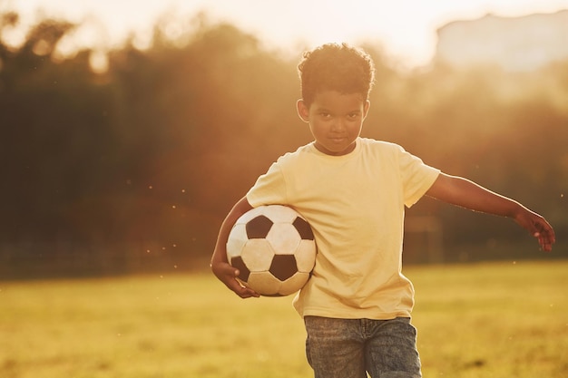 Young soccer player African american kid have fun in the field at summer daytime