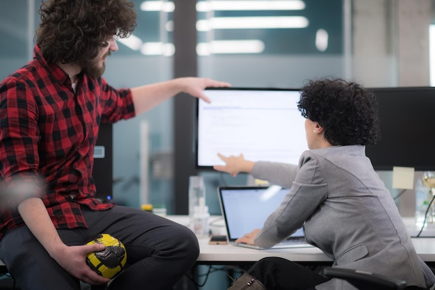 young software developers couple using laptop and desktop computer while writing programming code at modern creative startup office