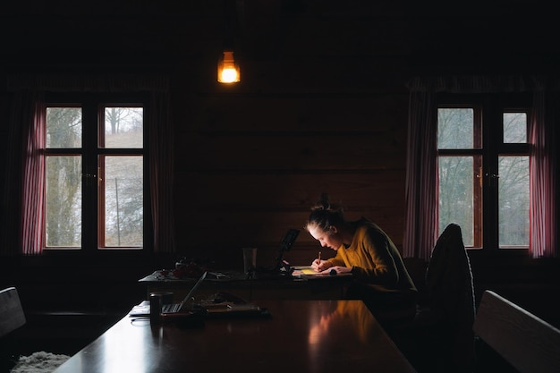 Young woman painting on paper on table at home