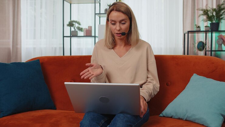 Foto young woman using laptop while sitting on sofa at home