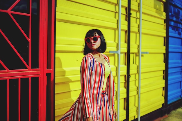 Young woman wearing sunglasses standing against building in city