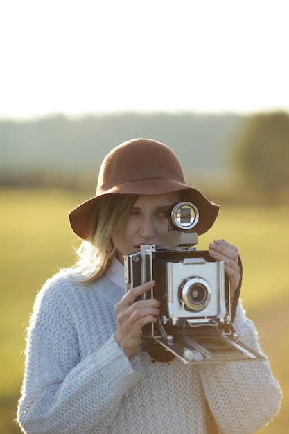young woman with camera standing on field