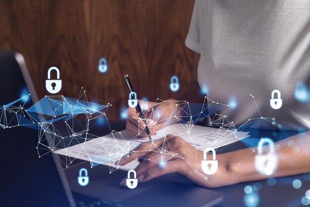 A businesswoman in casual wear signing the contract to prevent probability of risks in cyber security Padlock Hologram icons over the working desk