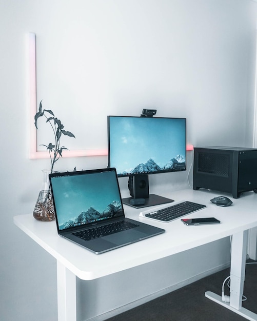 A laptop and a desktop on a white table