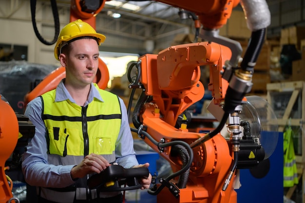 A male worker is controlling a welding robot by using forcing welding with a control screen