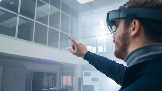 A man in a virtual reality glasses points to a screen that says vr on it.