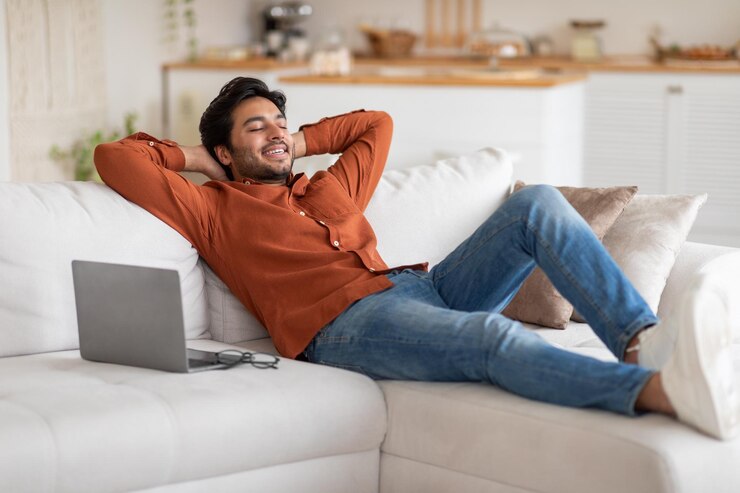 Foto a man is relaxing on a white couch leaning back with his arms behind his head he is wearing an