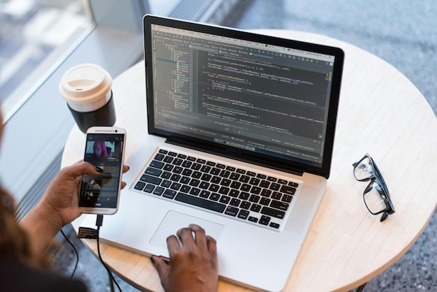 a person is using a phone and a laptop with the screen open to show the text code