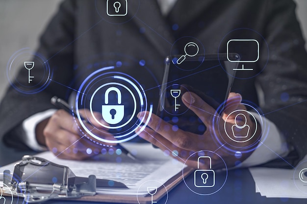 african american businesswoman in formal wear signing the contract to prevent probability of risks in cyber security checking the phone padlock hologram icons over the working desk