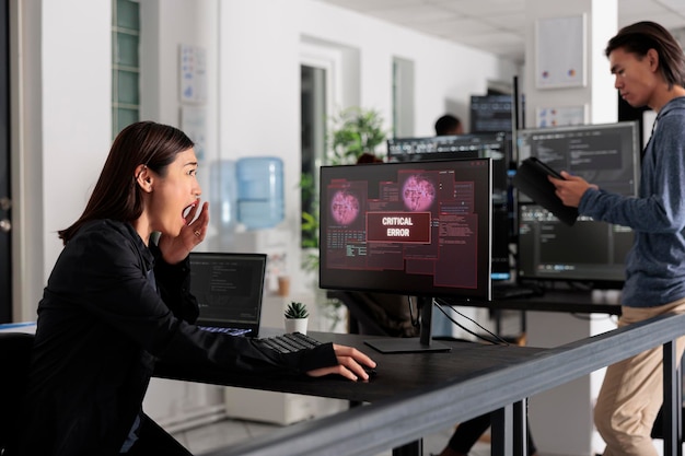 Asian app developer having web server hacked, analyzing critical error on programming computer monitor in office. Software developer trying to solve hacking problem, firewall security.