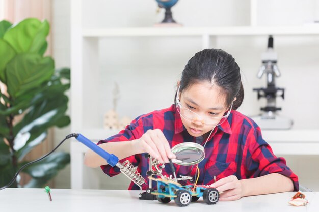 Asian child girl students build robotic cars kids learn to program robot vehicles