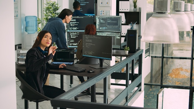 Asian data admin working with hologram and coding language in programming agency office. Analyzing holographic html script and augmented reality to develop new server interface.