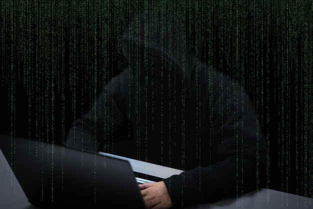 Asian hacker in black hood with matrix background