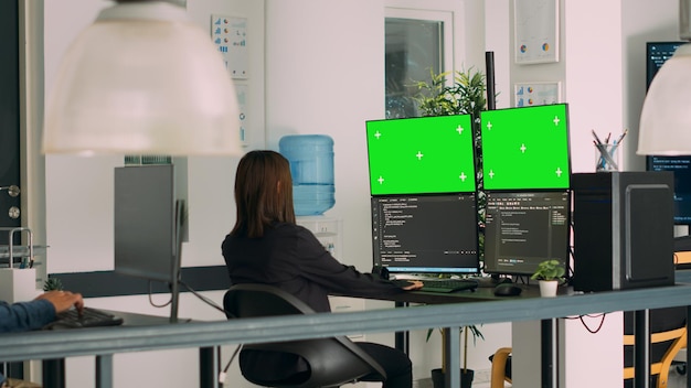 Asian system engineer using html script code and greenscreen on multiple monitors in software innovation office. Programmer working with terminal window and isolated chromakey display. Tripod shot.