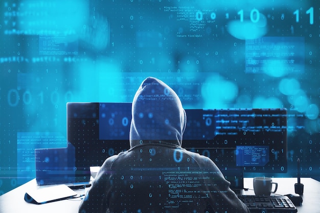 Back view of hacker at desktop using computer with abstract glowing blue coding background Binary code theft technology data and internet concept Double exposure