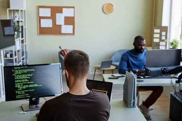 Background image of it company office with man writing code in green lines copy space