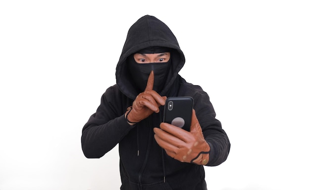 Bad guy in his black hoodie threatening his online victim using smartphone in his hand