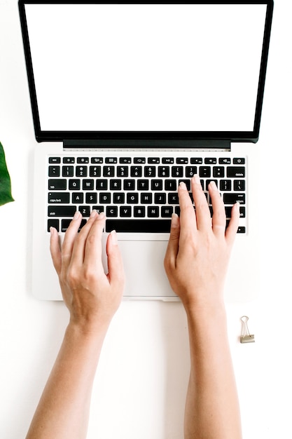 Bærbar computer med blank skærm og hænder, der skriver på tastaturet