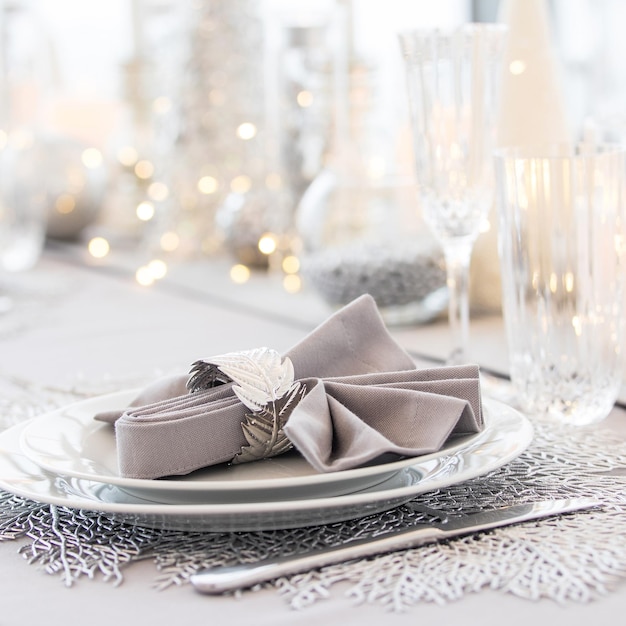 Beautiful table setting with Christmas decorations. Silver colors