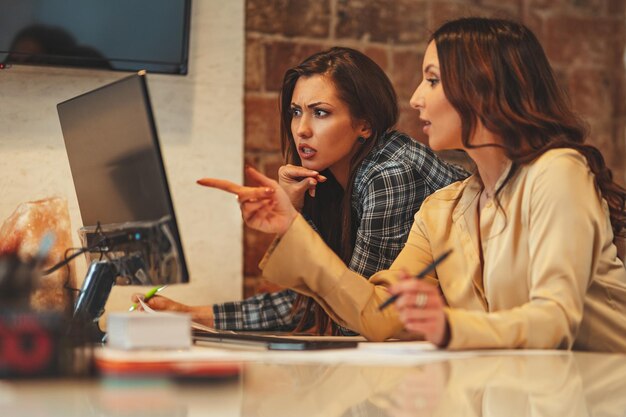 Beautiful young successful worried business women are analyzing new project on the computer in the office.