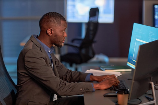 Black IT developer wearing suit while working on data project in office