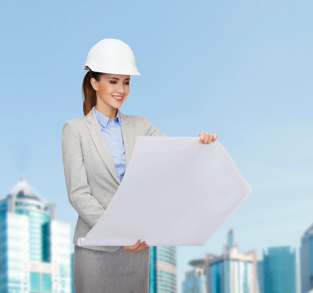 building, developing, consrtuction and architecture concept - friendly young smiling architect in white helmet with blueprints