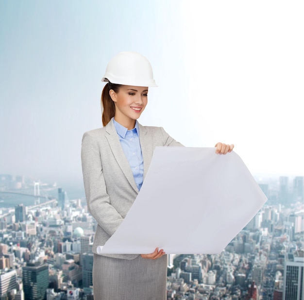 building, developing, consrtuction and architecture concept - friendly young smiling architect in white helmet with blueprints