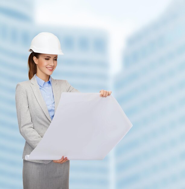 building, developing, consrtuction and architecture concept - friendly young smiling architect in white helmet with blueprints