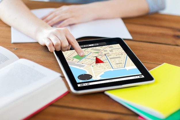 business, education, technology and location concept - close up of student woman with gps navigator map on tablet pc computer screen and notebook at home with gps navigator map on screen