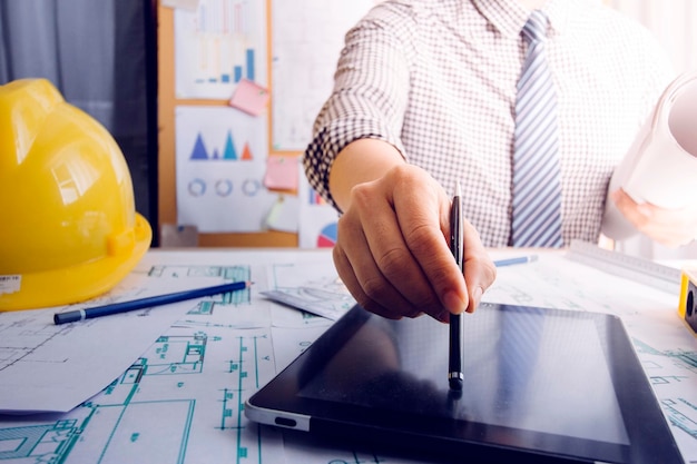 business hand working and laptop with on on architectural project at construction site at office desk in office