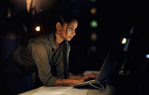 Business woman night and computer coding with web layout deadline and ux programmer in office Internet typing and online at workplace with website update and coder with digital project in dark
