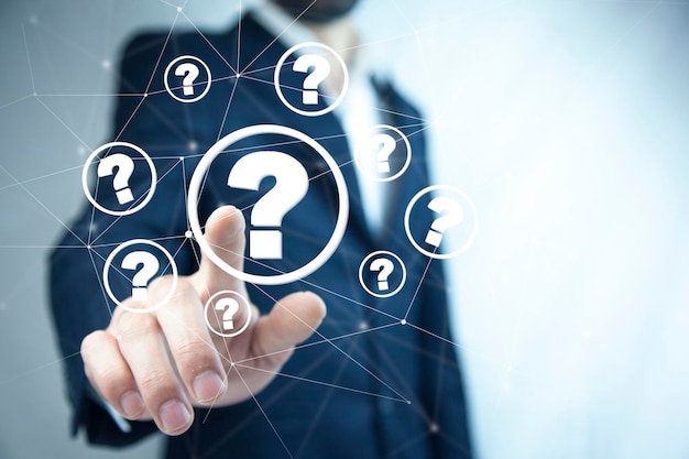 Businessman on blurred background holding hand drawn question marks