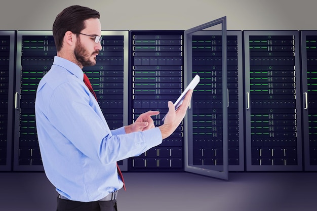 Businessman scrolling on his digital tablet against server towers