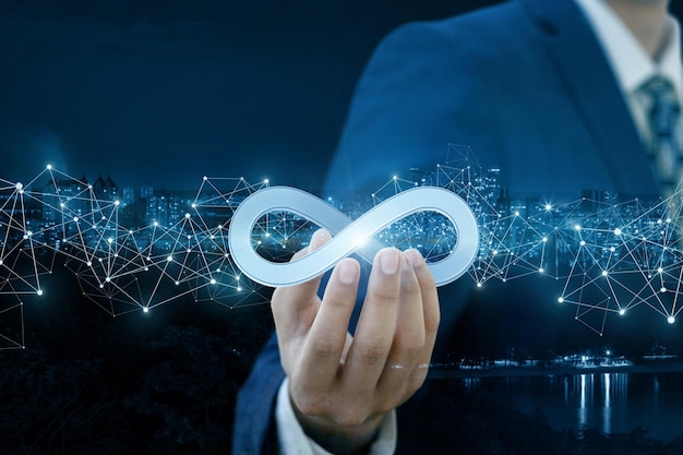 Businessman shows sign of infinity on the background of the city The concept of unlimited Internet