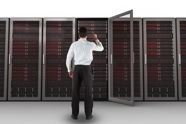 Businessman standing back to the camera pointing against server towers