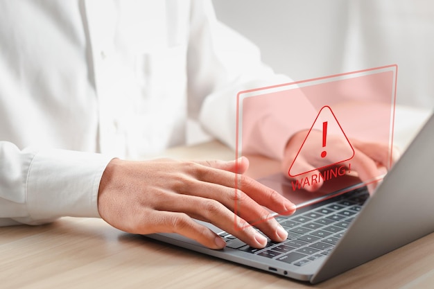 Businessman using laptop with warning sign for error notification Maintenance concept