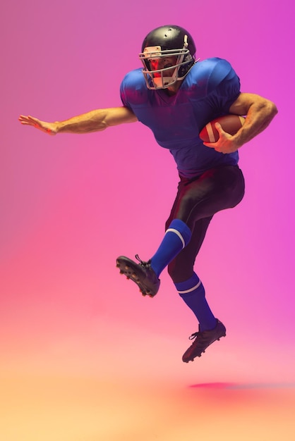caucasian male american football player holding ball with neon pink lighting