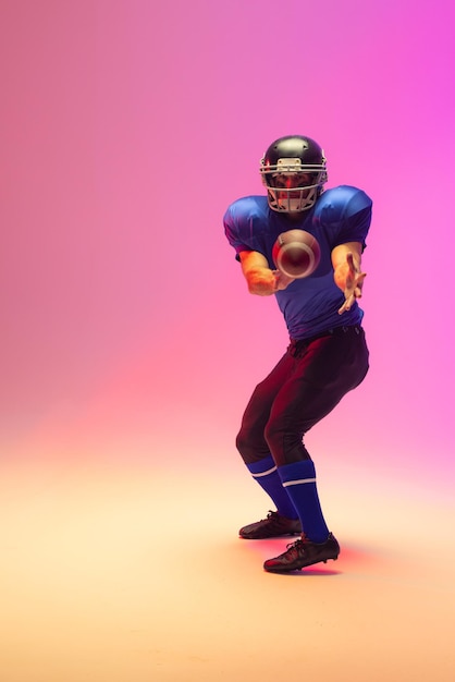 caucasian male american football player holding ball with neon pink lighting