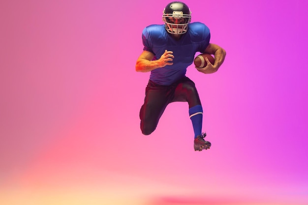 caucasian male american football player holding ball with neon pink lighting