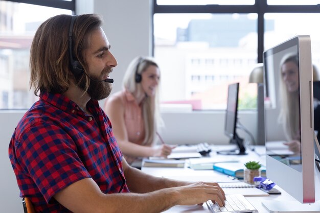 Caucasian man and woman wearing phone headset in modern office. communication and social distancing in business office workplace during covid 19 coronavirus pandemic.