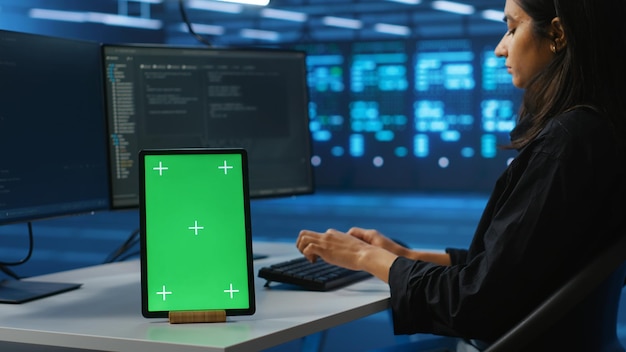 Chroma key device on desk used by worker supervising data center supercomputers
