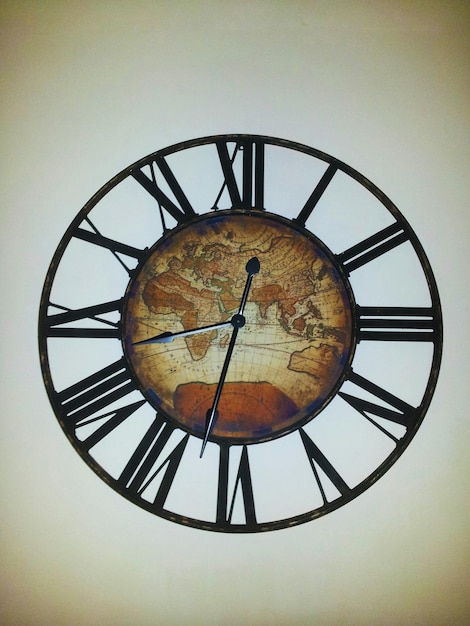 Close-up of clock with map on wall