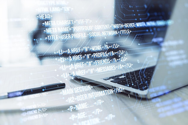 Close up of laptop on desk with pen notepad and creative digital programming language on blurry background Software developer and html concept Double exposure