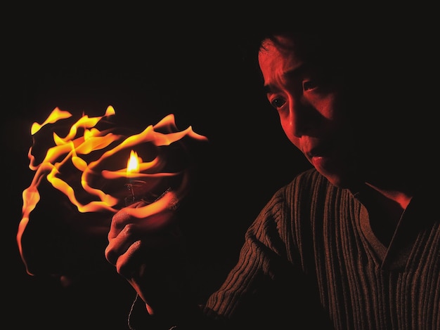 close-up of man holding cigarette lighter against black background