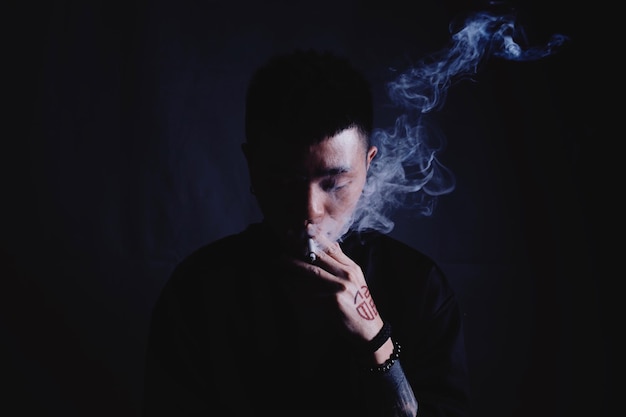 close-up of man smoking cigarette against black background