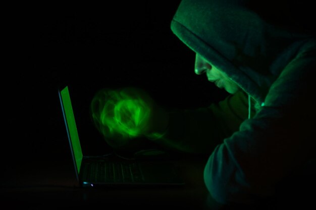 Close-up of man using laptop in darkroom at night