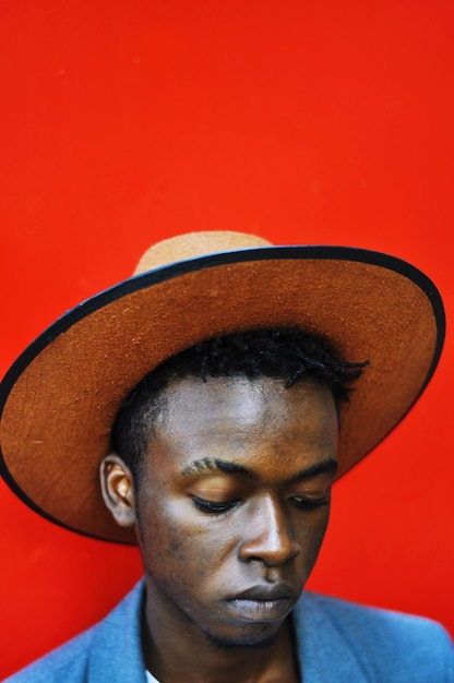 close-up of man wearing hat against red wall
