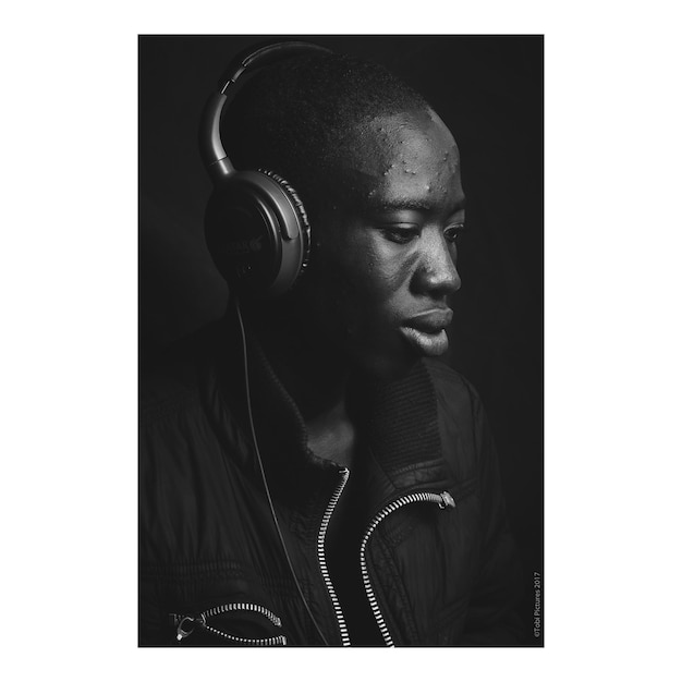 close-up of young man listening music against black background