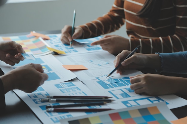 Close up ux developer and ui designer brainstorming about mobile app interface wireframe design on table with customer breif and color code at modern officeCreative digital development agency