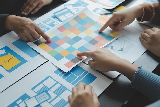 Close up ux developer and ui designer brainstorming about mobile app interface wireframe design on table with customer breif and color code at modern officeCreative digital development agency